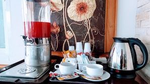 Een koffiehoek met een koffiezetapparaat, bekers en een waterkoker op een dienblad.