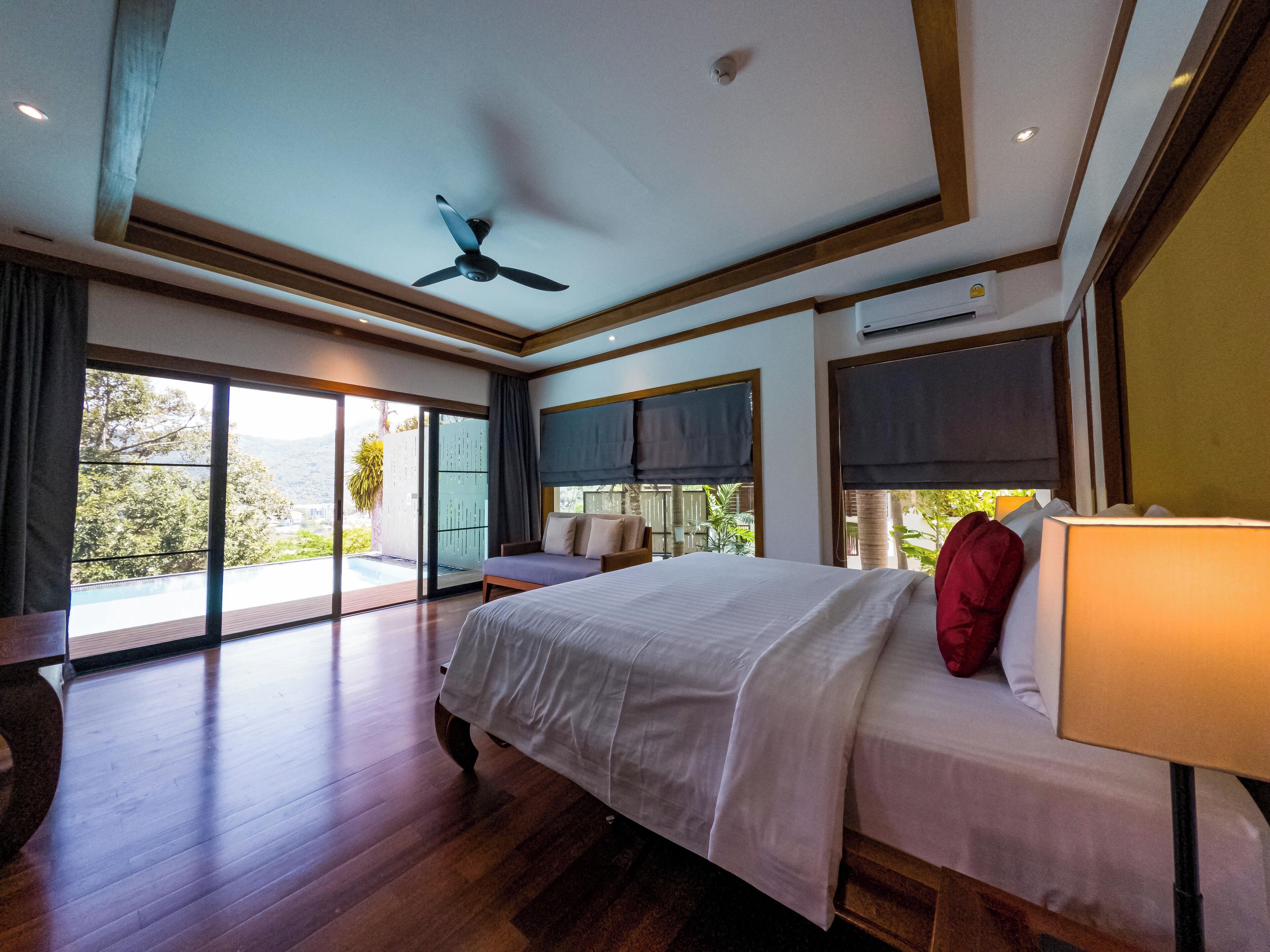 A spacious bedroom with a large bed, a ceiling fan, and a view of a balcony.