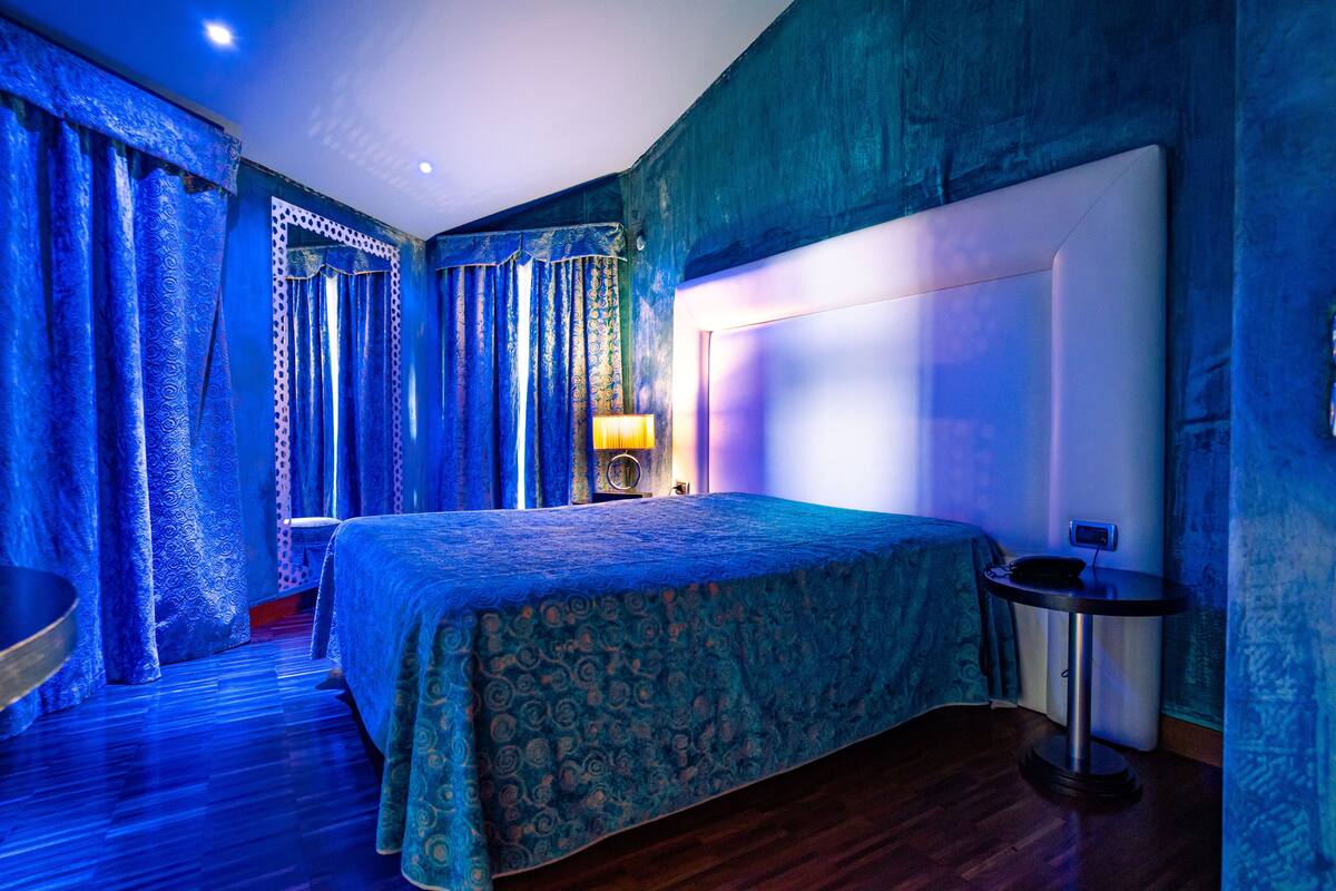 Une chambre à coucher avec un grand lit, une table de chevet et une lampe.