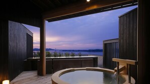 Un bain à remous avec une terrasse en bois et une vue sur la mer et les montagnes.