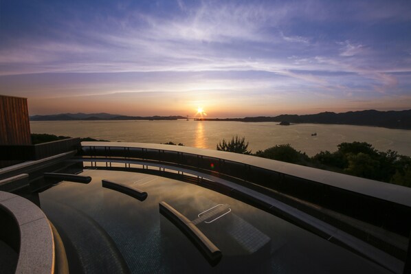 Un área de piscina moderna con vista al atardecer sobre un cuerpo de agua.