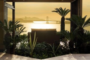Blick auf die Golden Gate Bridge durch eine Glaswand, umgeben von tropischen Pflanzen.