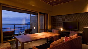 A balcony with a wooden table and chairs, a TV, and a checkered wall. - Hotel New Awaji (Sumoto)