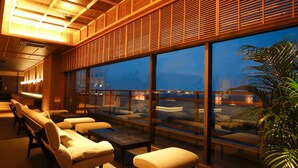 A modern lounge area with seating and large windows offering a view of the cityscape. - Hotel New Awaji (Sumoto)