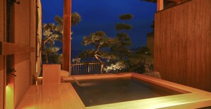 A wooden hot spring bath with a view of pine trees and a wooden fence. - Hotel New Awaji (Sumoto)