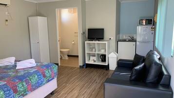 Habitación de hotel con cama, televisor, sofá, kitchenette y baño.