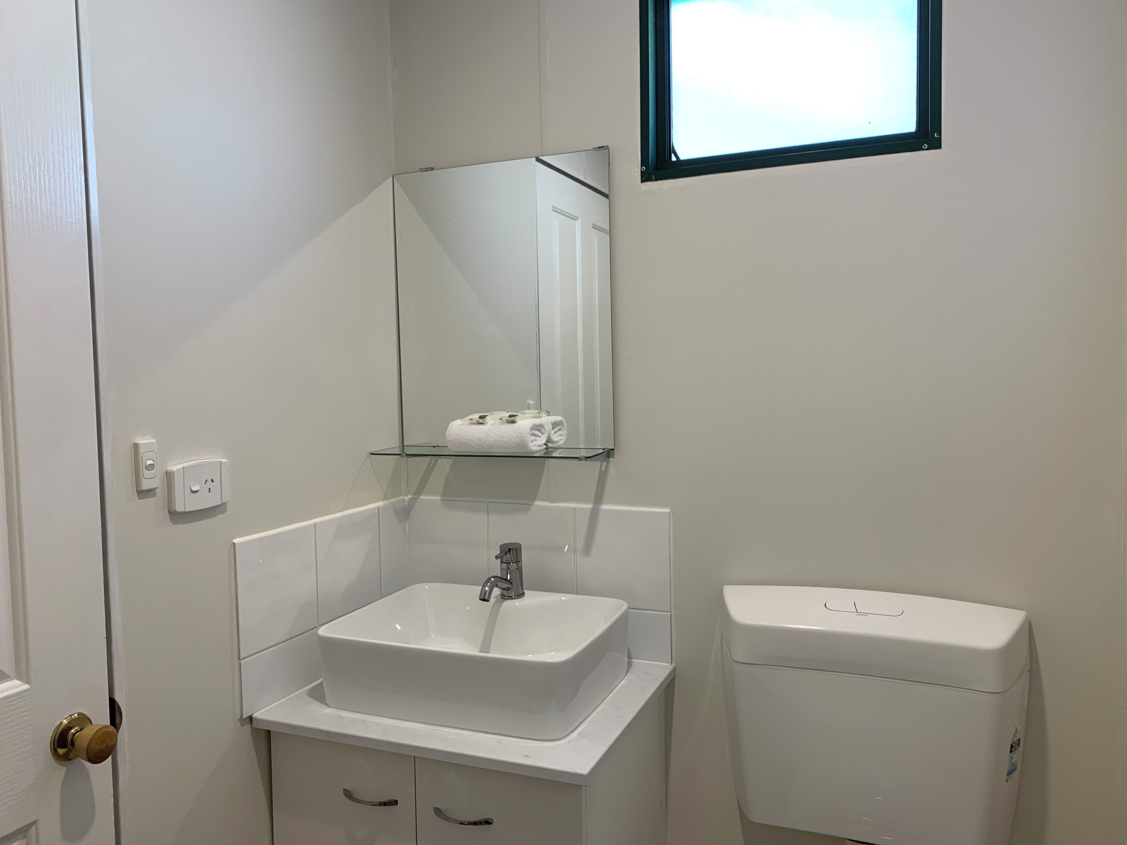 A bathroom with a white sink, mirror, and toilet.