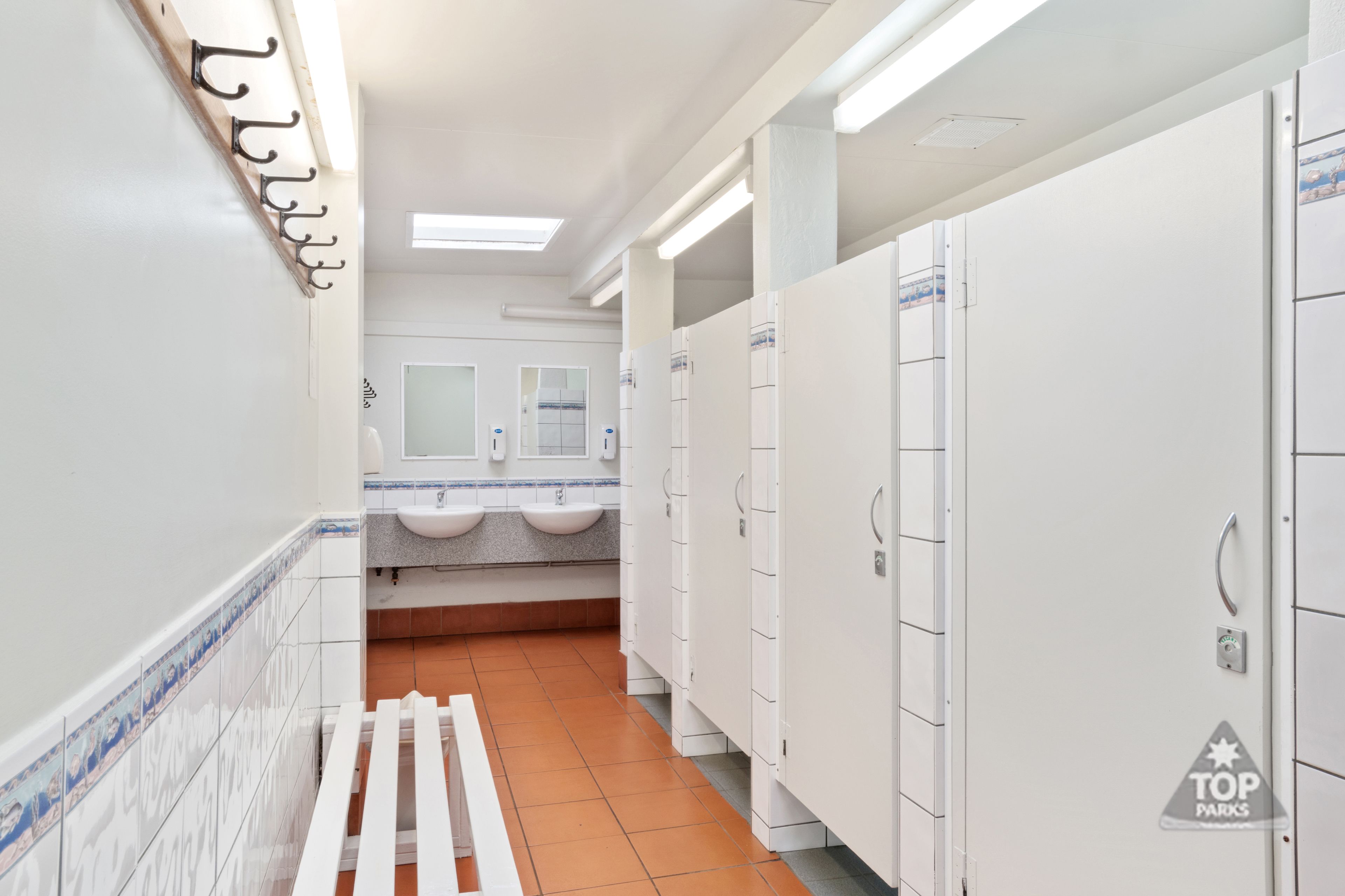 A restroom with white lockers, sinks, and a tiled floor.