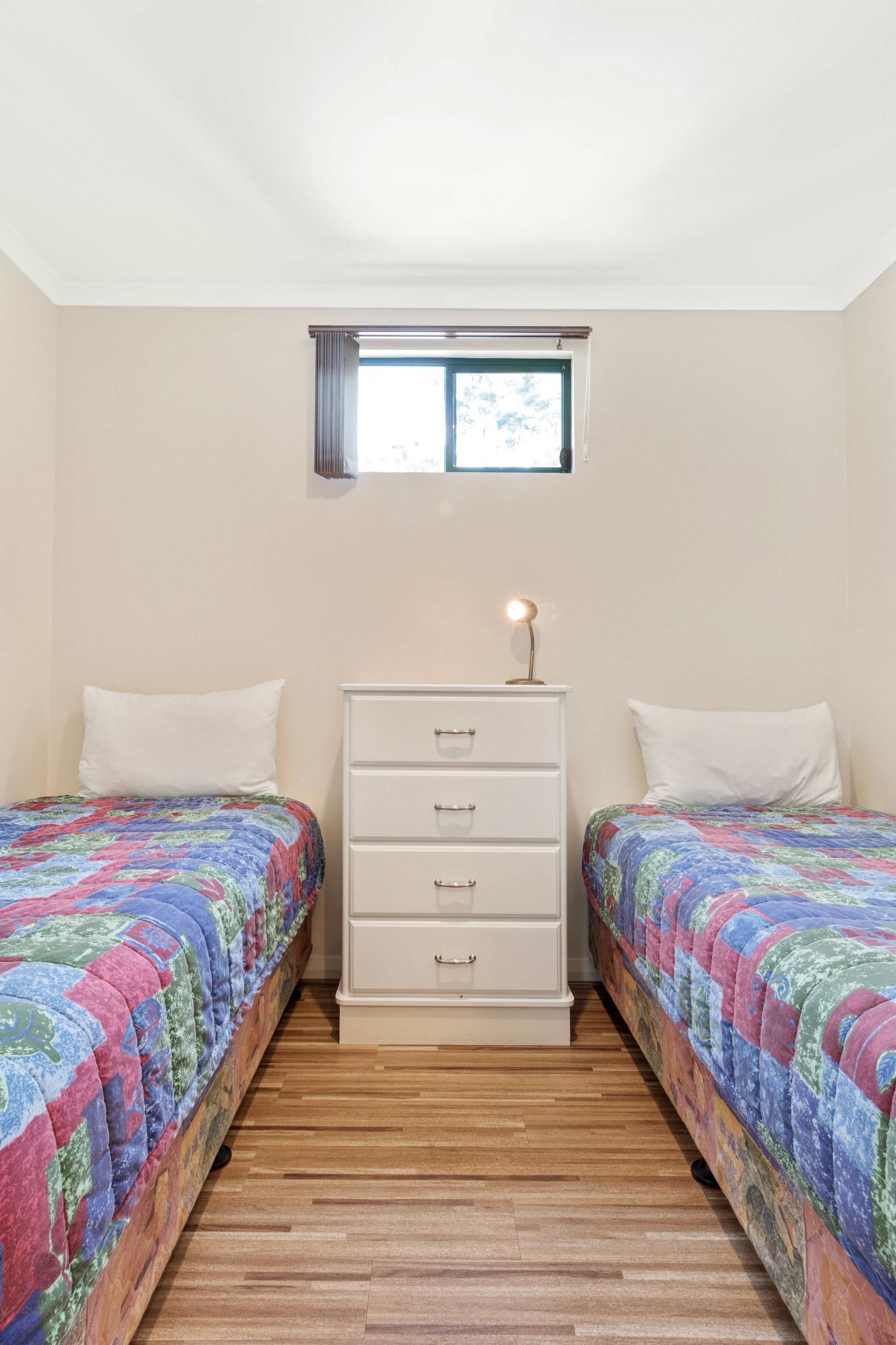 Un dormitorio con dos camas, un aparador y una ventana.