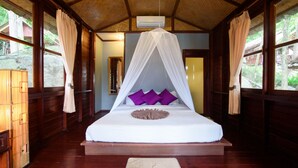 A room with a bed under a canopy, wooden walls, and large windows.