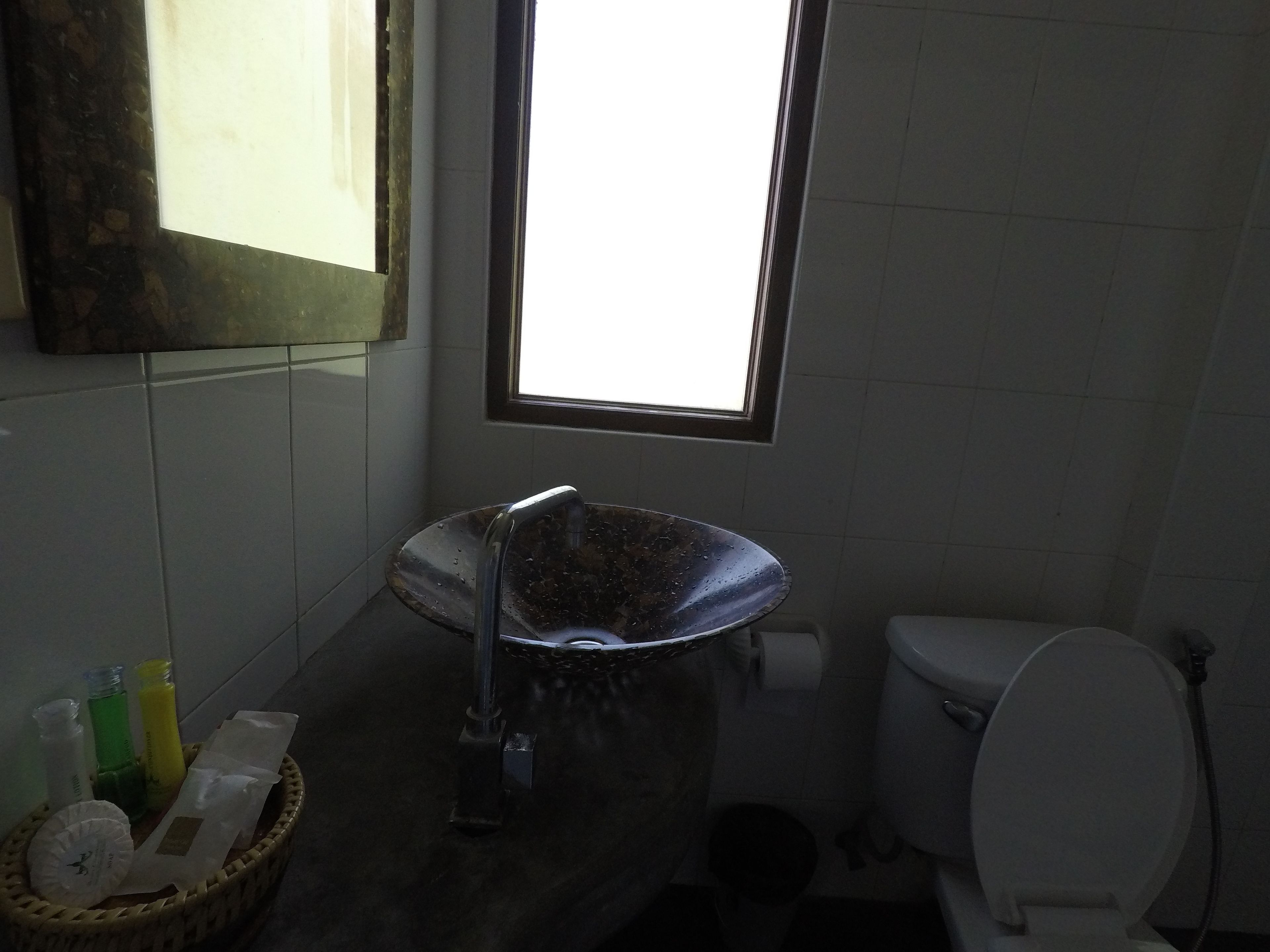 A bathroom with a sink, toilet, and a window.