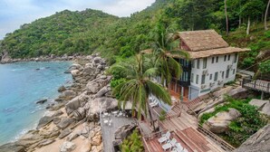 A coastal property with a wooden deck, outdoor seating, and a view of the sea.