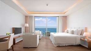 Una habitación de hotel con un ventanal grande, una cama, un escritorio, una silla y un televisor.
