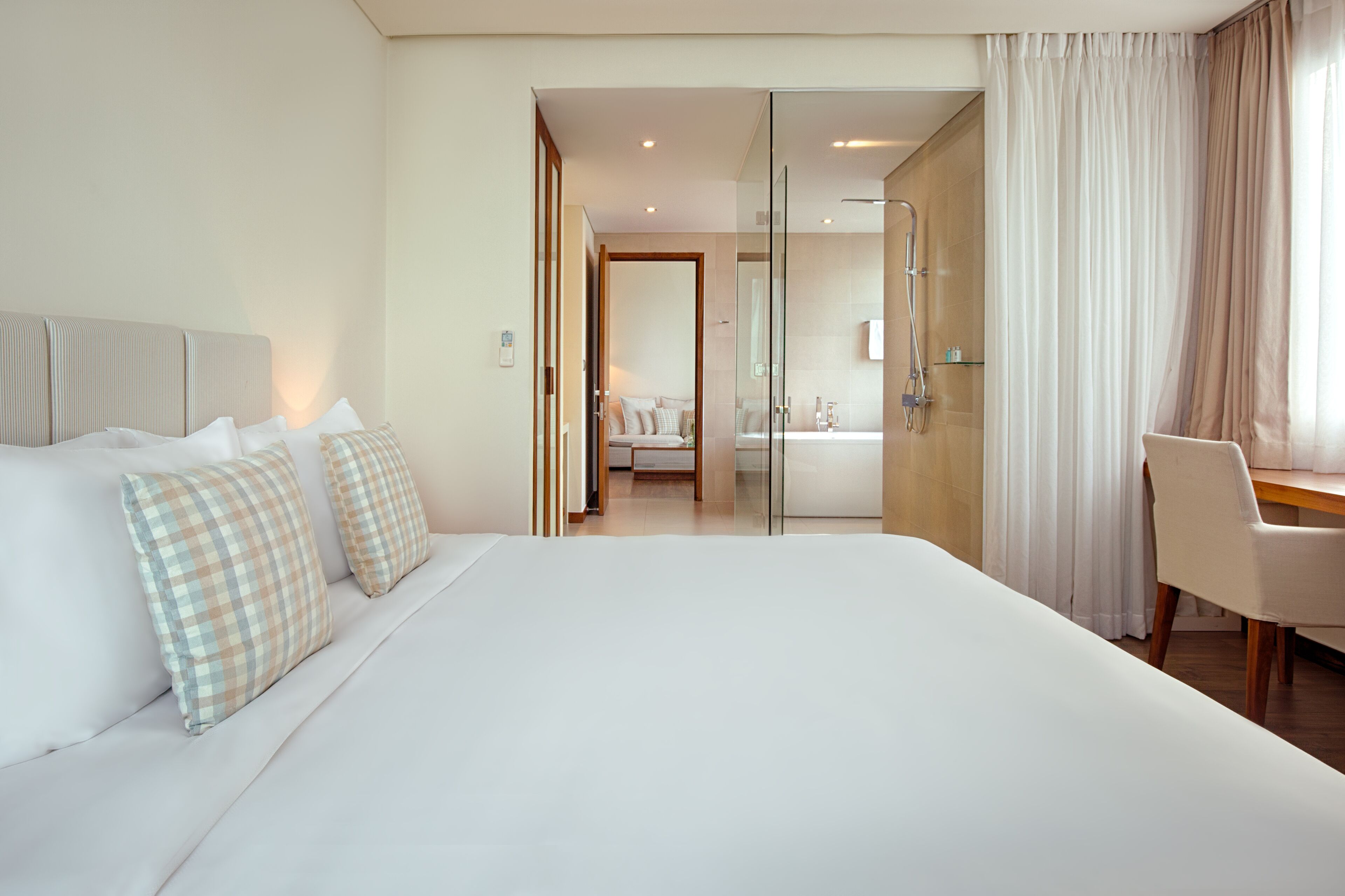 A hotel room with a large bed, a desk, and a bathroom visible through an open door.