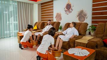 A modern spa room with multiple massage chairs, a wooden foot bath, and a large window with curtains.