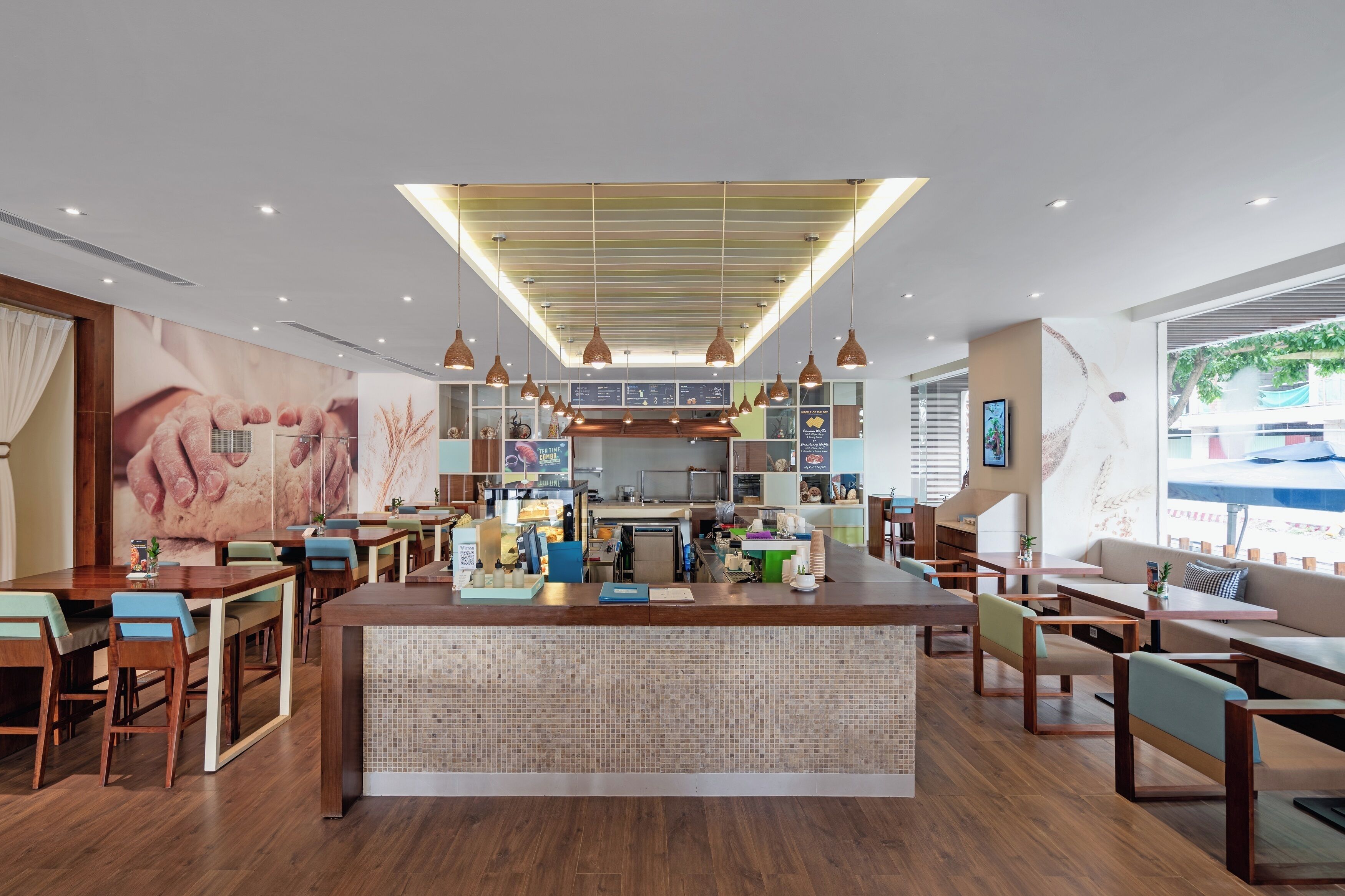 A modern restaurant with a central island, wooden tables and chairs, and a large mural on the wall.