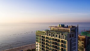 A high-rise hotel with balconies overlooking a beach and the sea.