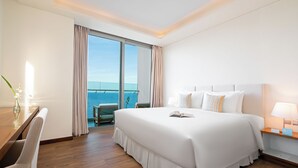 A hotel room with a large bed, a desk, and a view of the ocean.