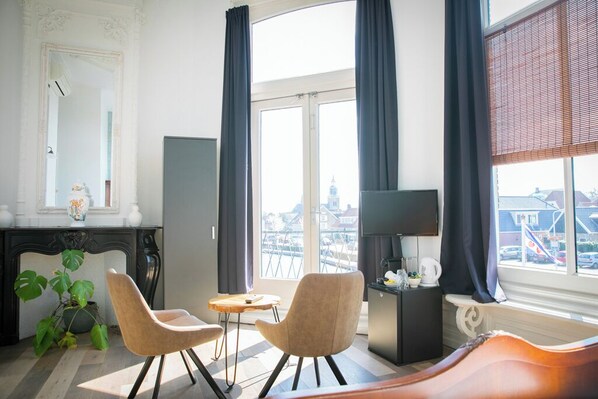 Una sala de estar moderna con un ventanal grande, una chimenea, dos sillones, una mesita y un televisor.