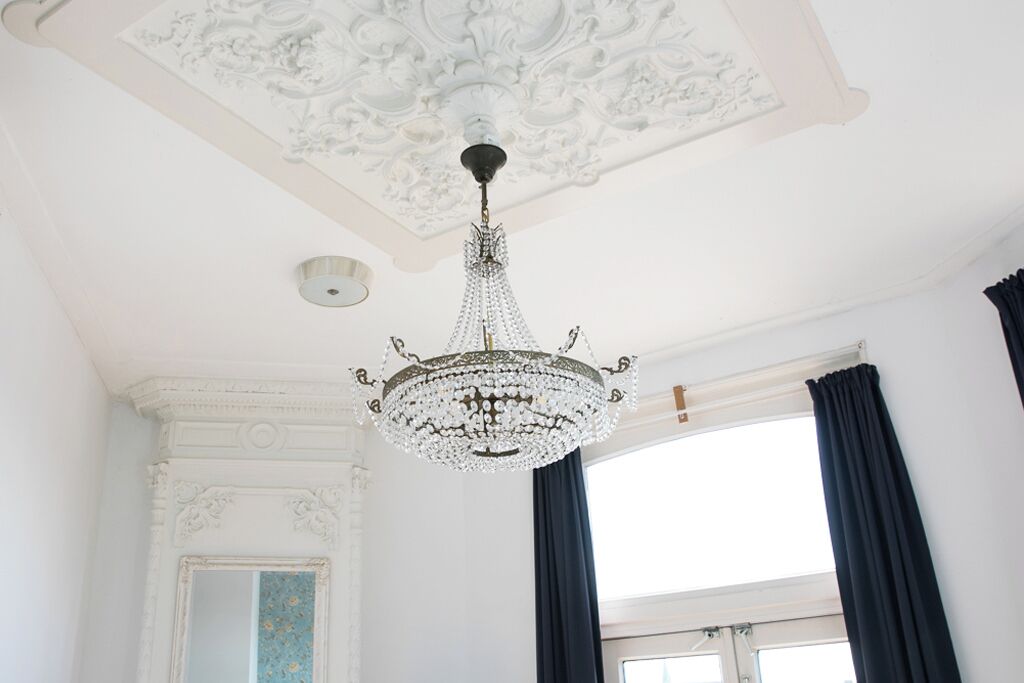 A room with a chandelier, a window with curtains, and a decorative ceiling.