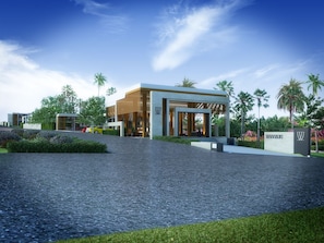 A modern building with a paved entrance area, surrounded by greenery and palm trees. - Wanaburi Hotel (Thep Kasattri)