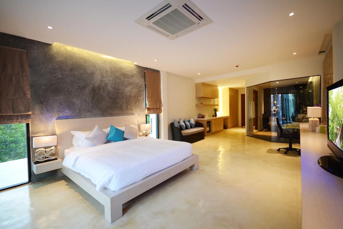 A modern bedroom with a large bed, bedside tables, a TV, and a view of the outdoors.