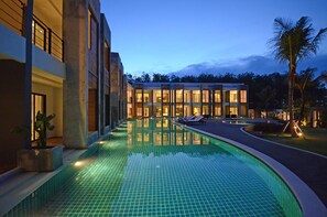 A modern hotel with a swimming pool, multiple balconies, and a well-lit exterior at dusk. - Wanaburi Hotel (Thep Kasattri)