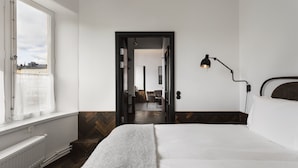 A hotel room with a bed, a desk, a chair, a lamp, and a view of the city through a window. - Miss Clara by Nobis, Stockholm, a Member of Design Hotels (Stockholm)