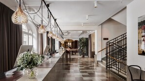 A modern hotel lobby with a check-in counter, a staircase, and a large potted plant. - Miss Clara by Nobis, Stockholm, a Member of Design Hotels (Stockholm)