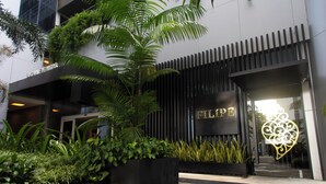 A modern building entrance with a name sign, lush greenery, and a decorative glass feature. - Bugan Recife Boa Viagem Hotel - by Atlantica (Recife)
