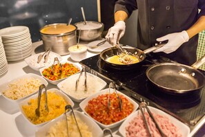 Montaje tipo bufé con diversas opciones de comida y una persona sirviendo.