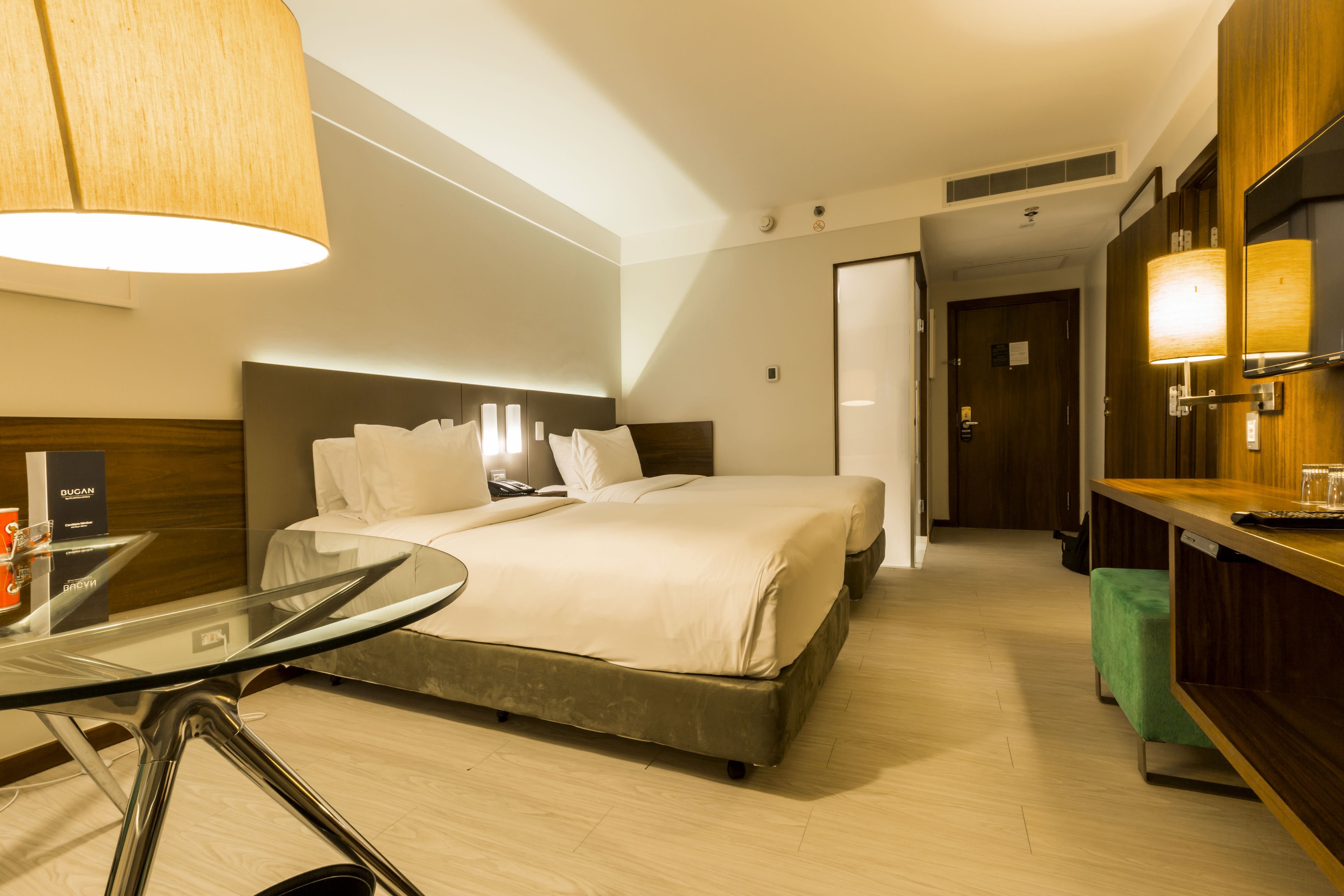 Een hotelkamer met een groot bed, een glazen tafel en een houten bureau.