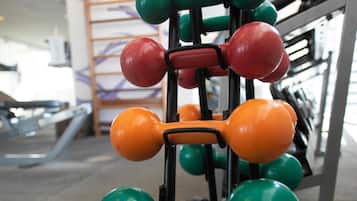 A weightlifting rack with various colored dumbbells.