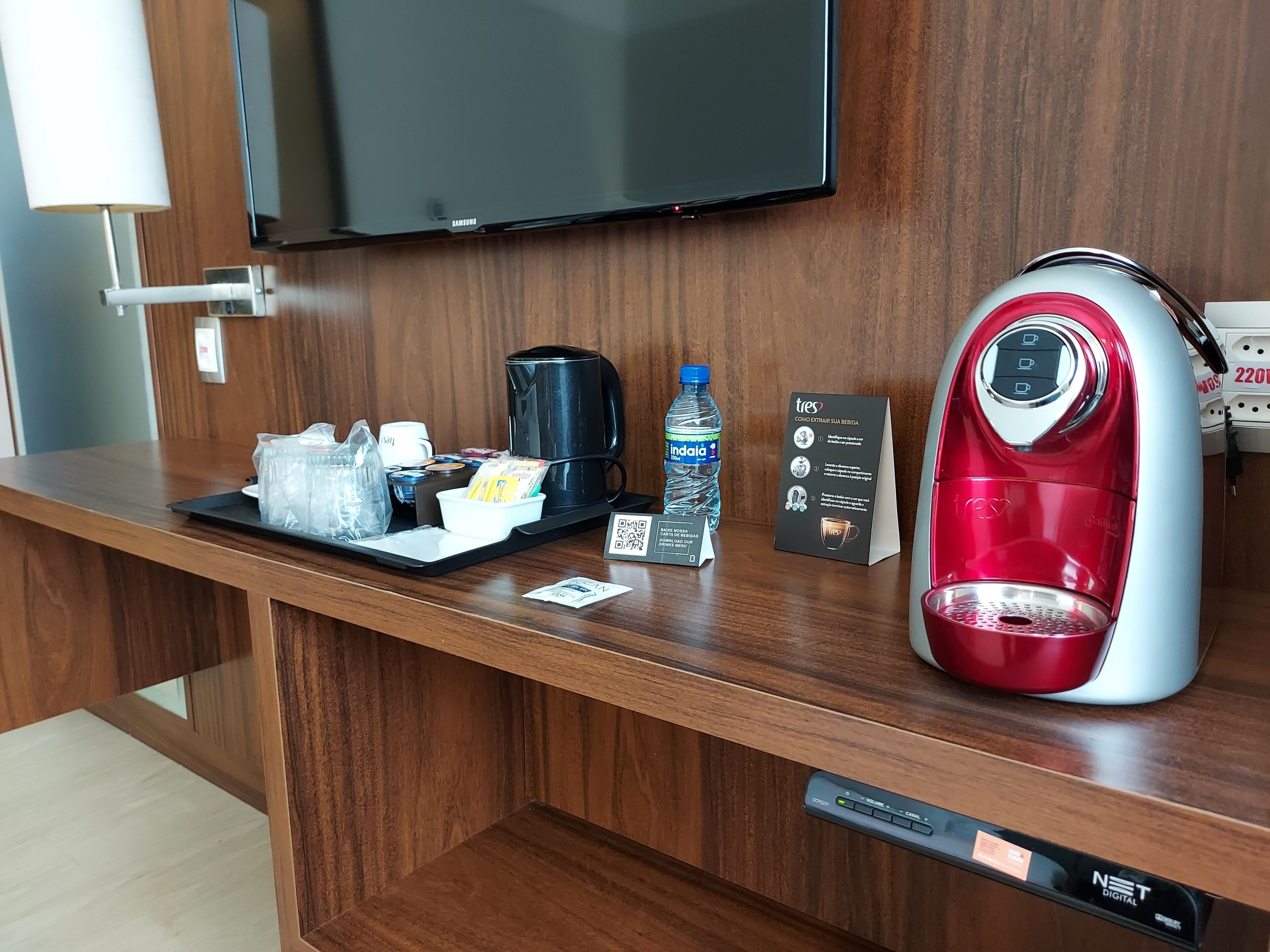 A hotel reception desk with a coffee maker, water bottle, and a sign with instructions.