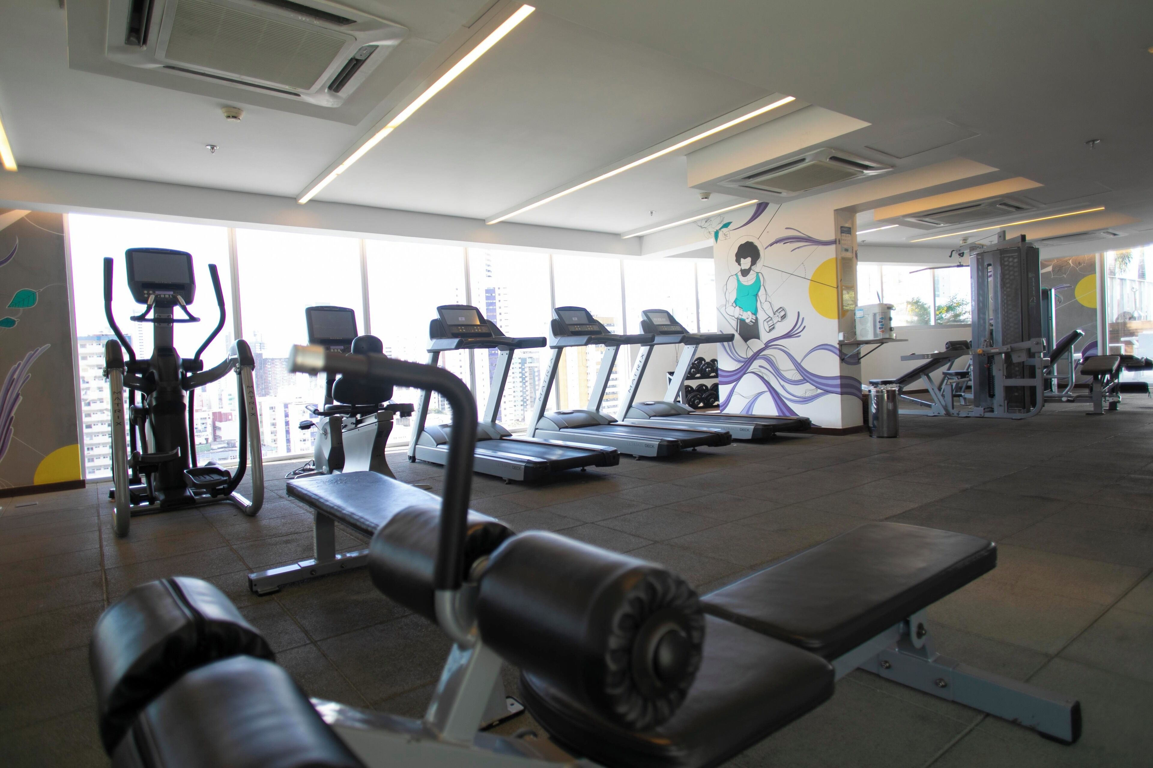 Un gimnasio con cintas de correr, máquinas de pesas y bancos.