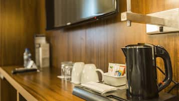 A wooden counter with a coffee maker, cups, and a tray.