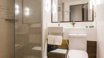 A modern bathroom with a glass-enclosed shower, a white toilet, and a sink with a mirror above it.