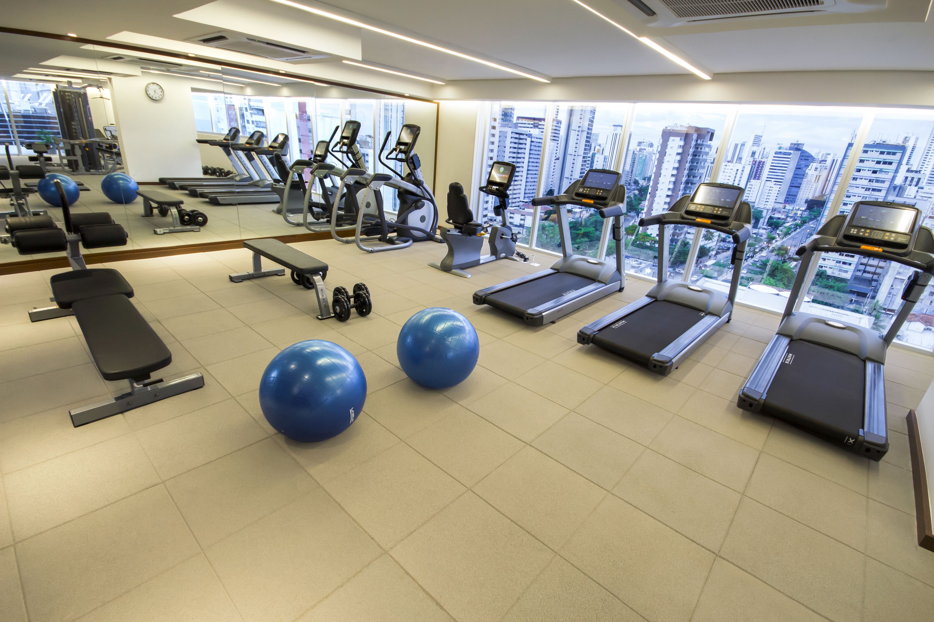 Un gimnasio moderno con cintas de correr, pelotas de ejercicio y máquinas de pesas.