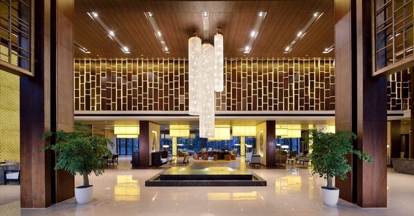 A spacious lobby with a central water feature, a reception desk, and seating areas. - Millennium Resort Hangzhou (Hangzhou)