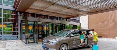 A modern building entrance with a car parked in front.