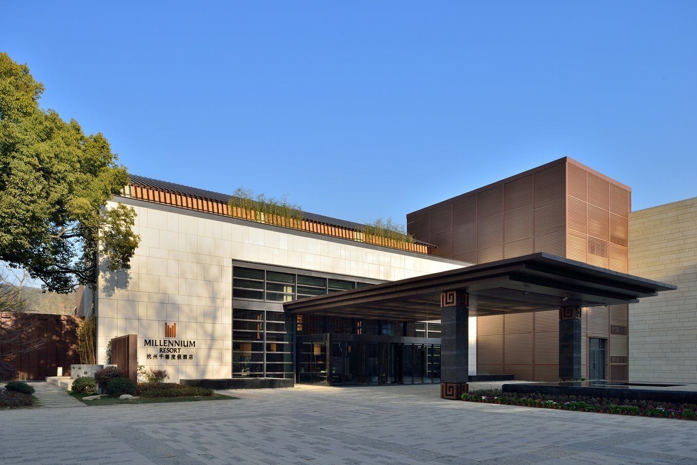 A modern building with a large entrance, a covered walkway, and a sign reading "Millennium Resort."