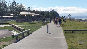 Un camino pavimentado en un parque con bancos y zonas de picnic.
