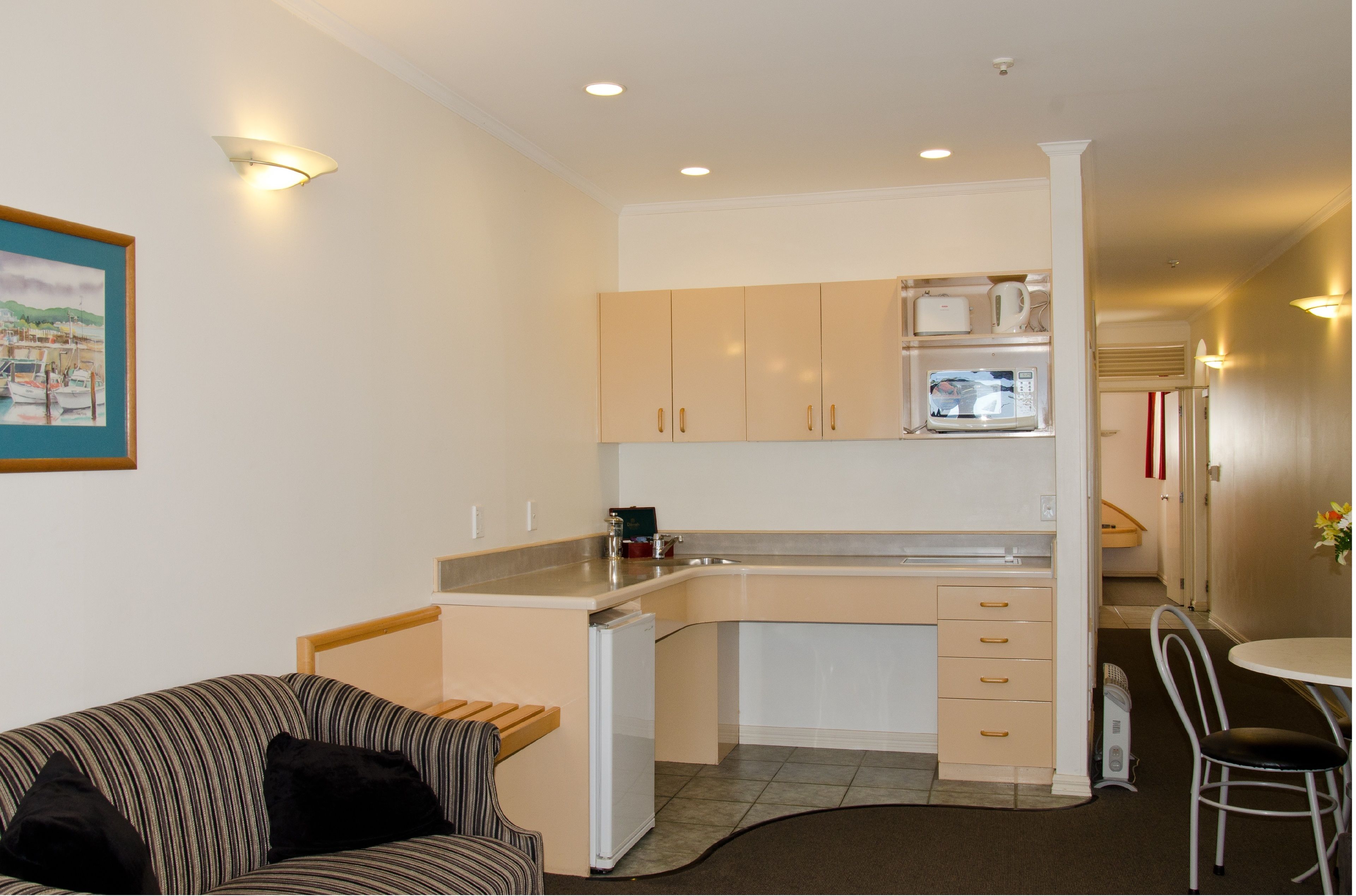A compact kitchen with a microwave, toaster, and refrigerator. There is a dining area with a table and chairs.