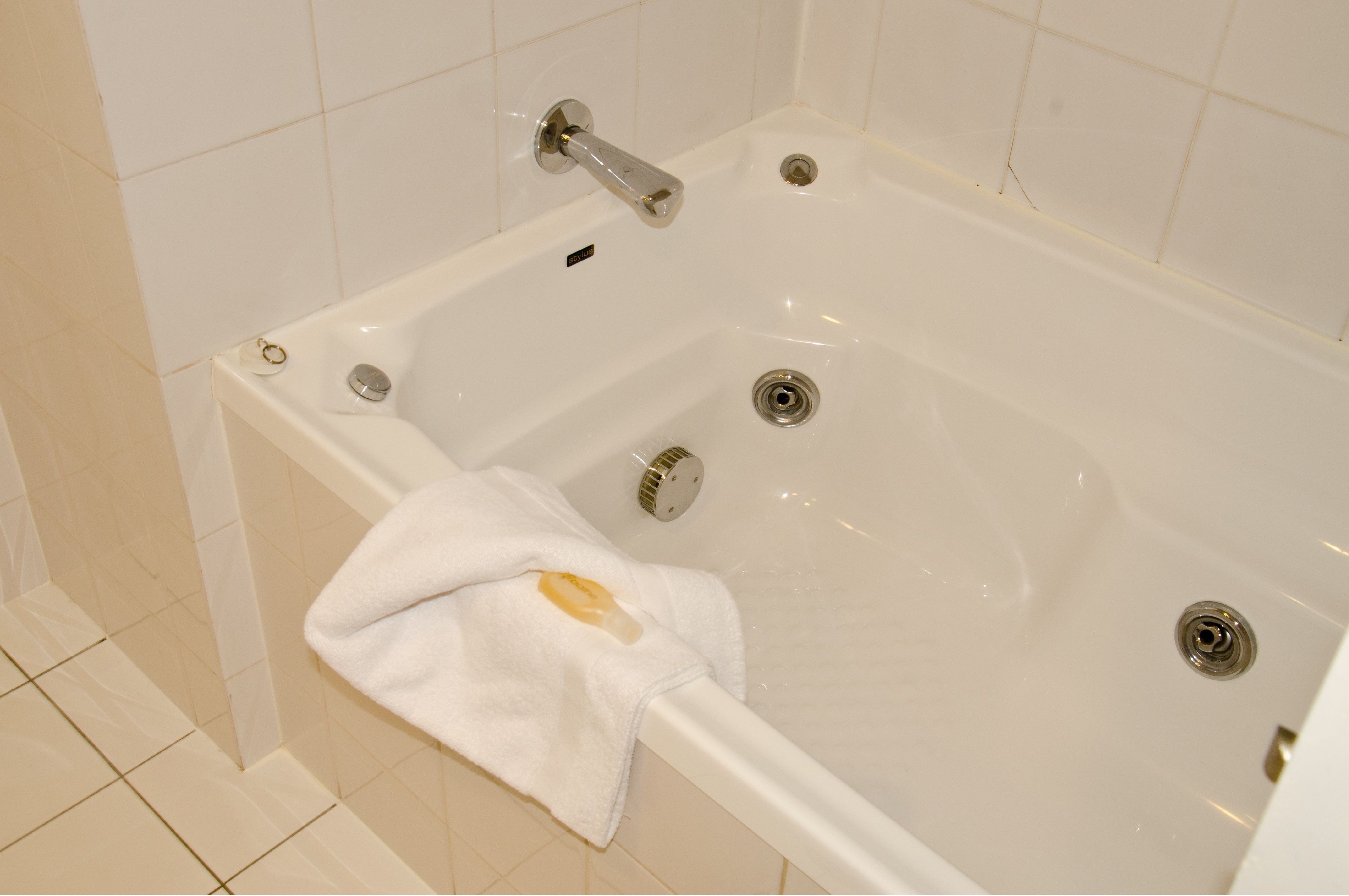 Una bañera blanca con ducha, una toalla y desagüe.
