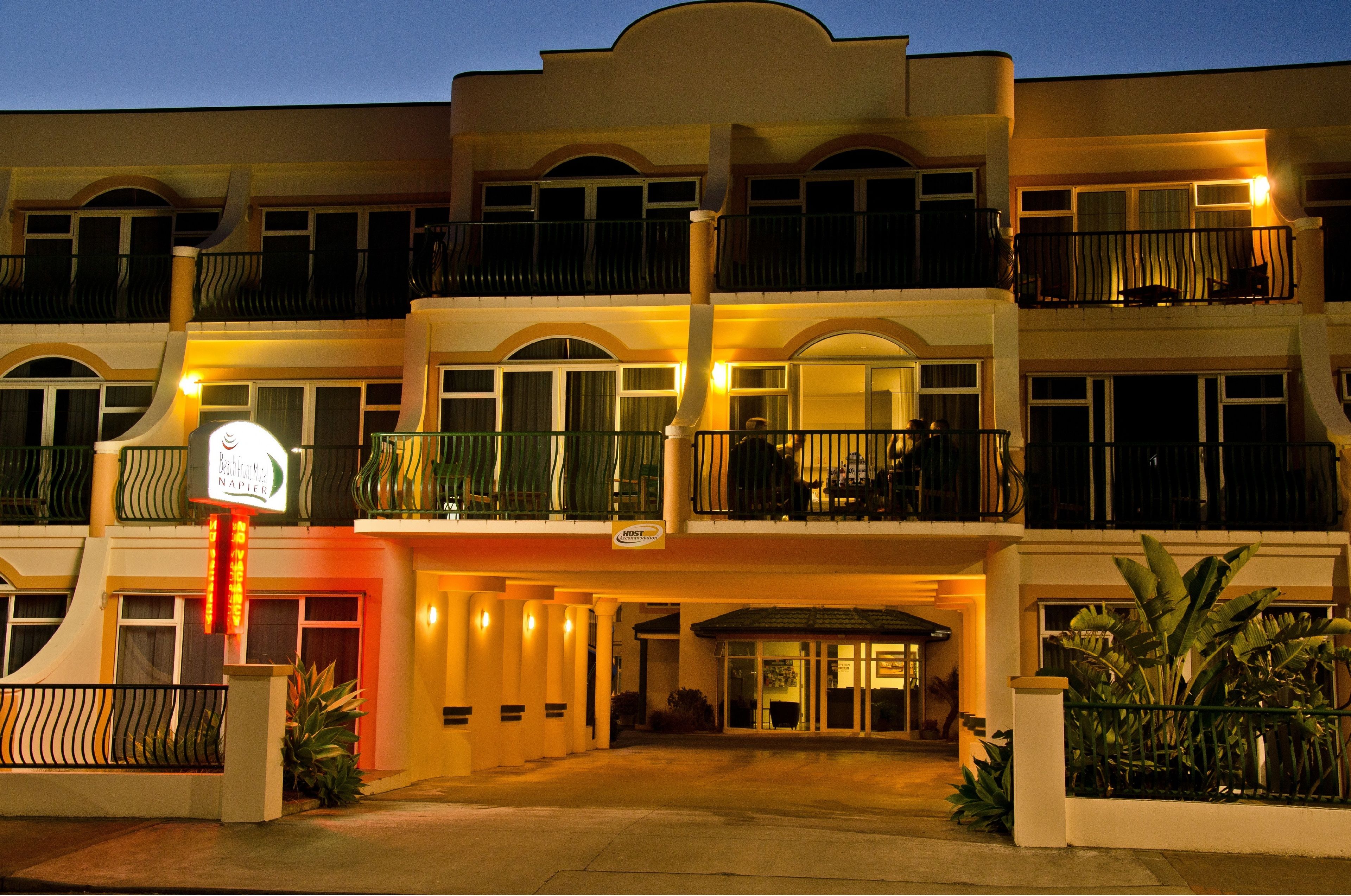 A multi-story hotel with a central entrance, balconies, and a sign indicating it is a hotel.