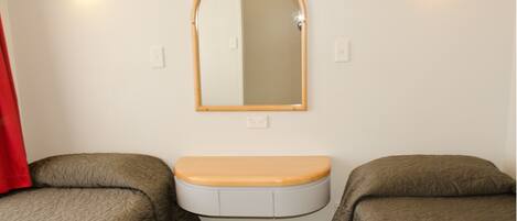 A bathroom with a toilet, a mirror, and two beds.