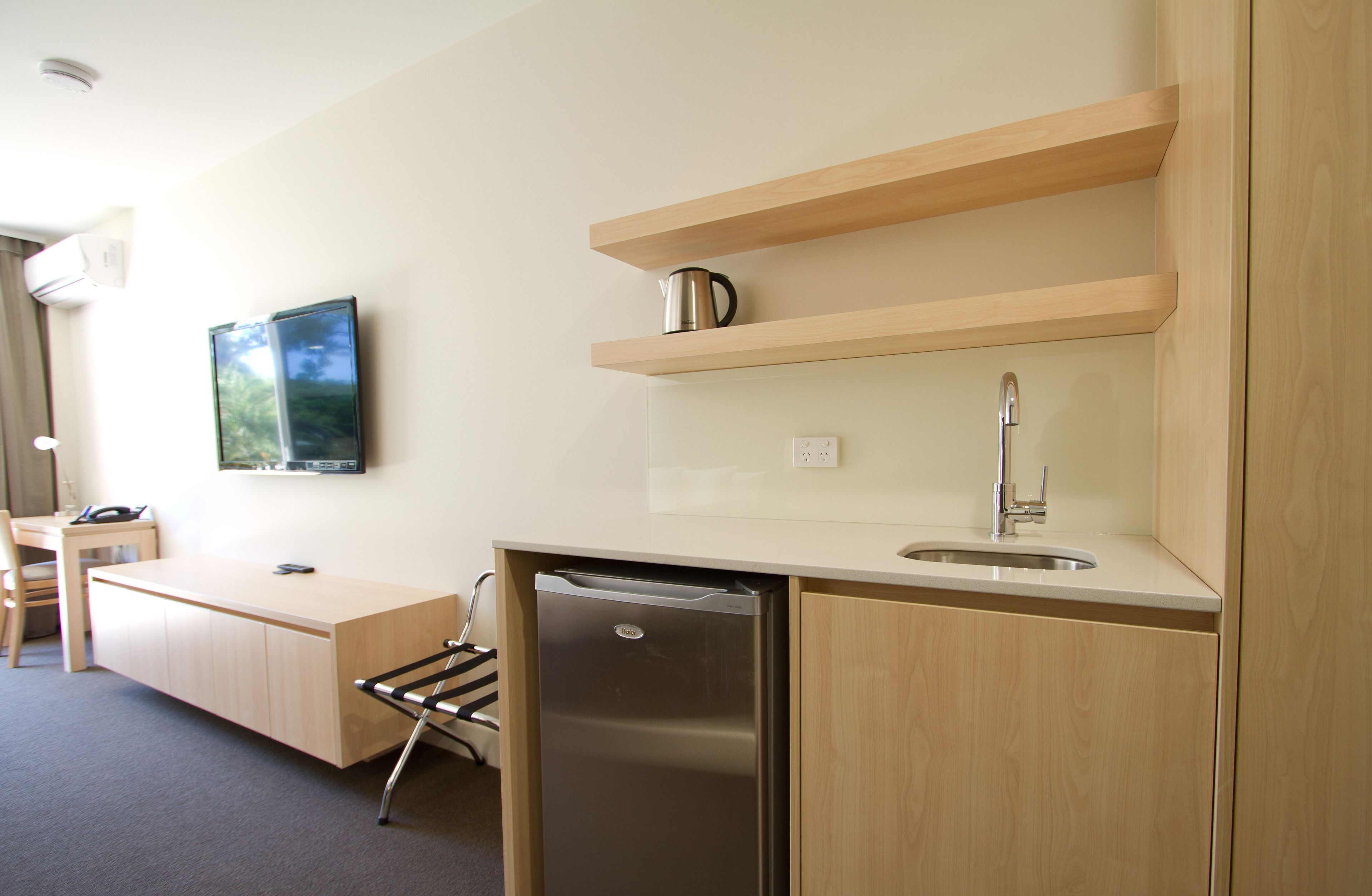 A modern kitchen with a built-in dishwasher, a sink, and wooden shelves.