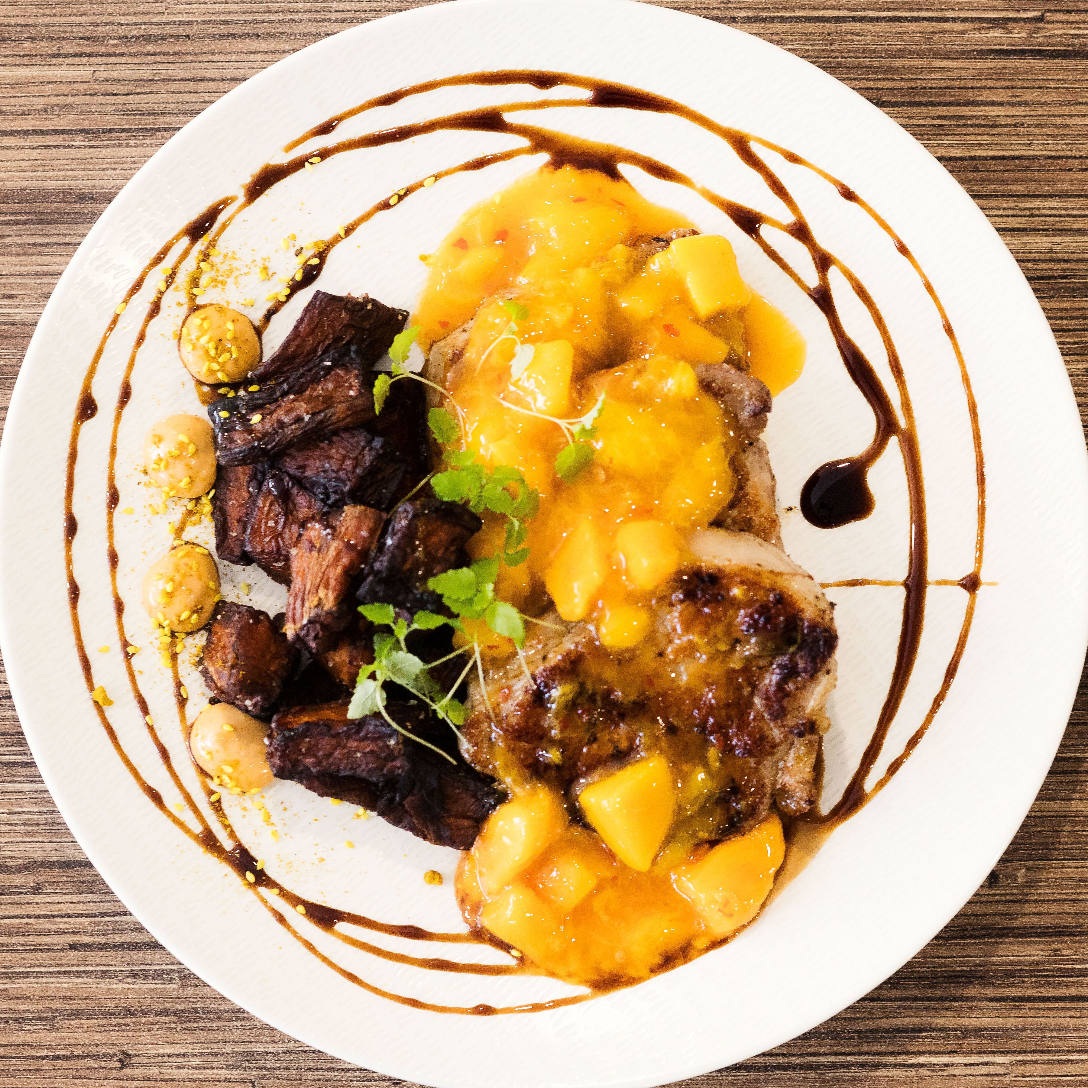 Un plato de comida con carne, mango y salsa.