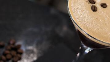 Primer plano de una bebida en un vaso, con una capa cremosa y granos de café encima.