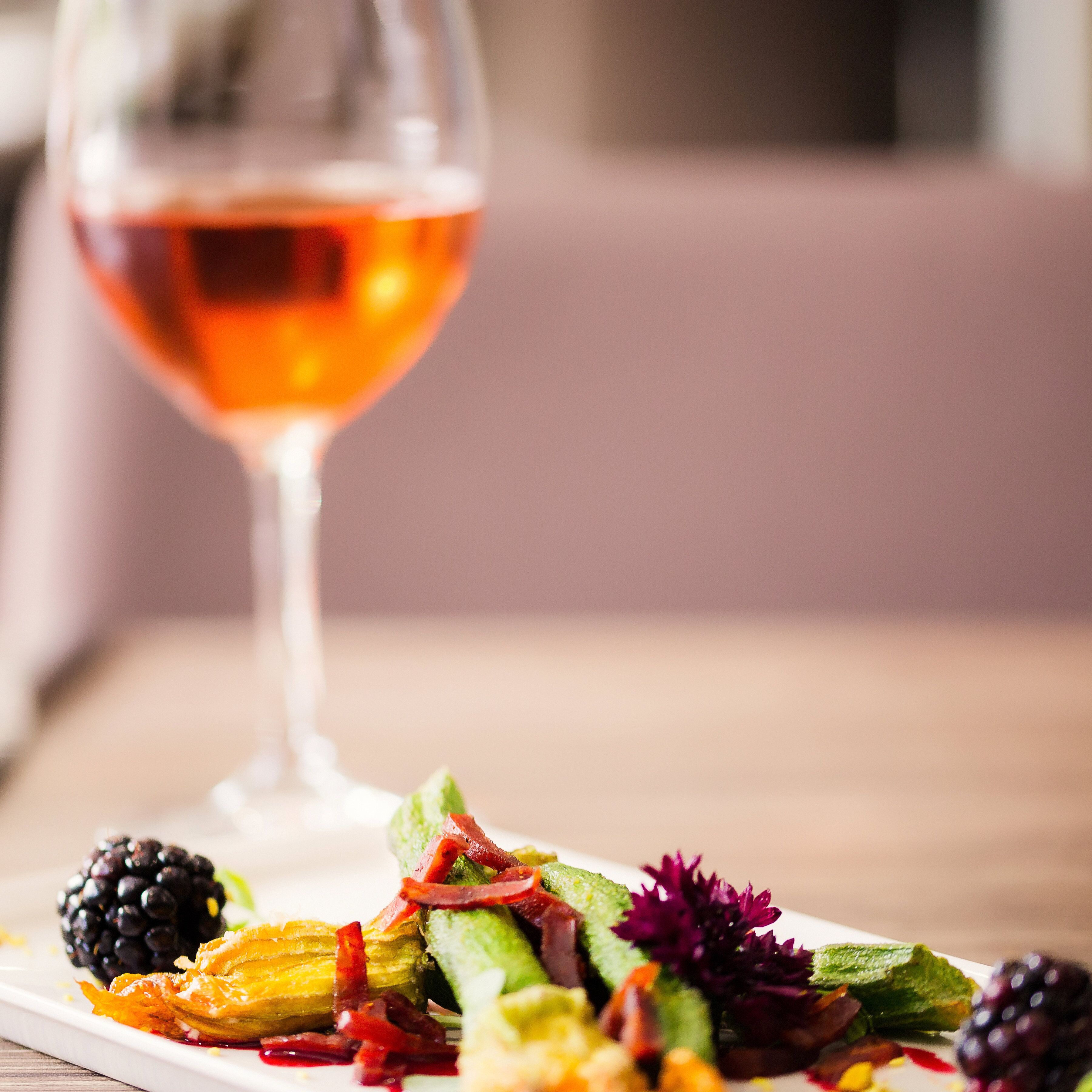 A dining table with a plate of food and a glass of wine.